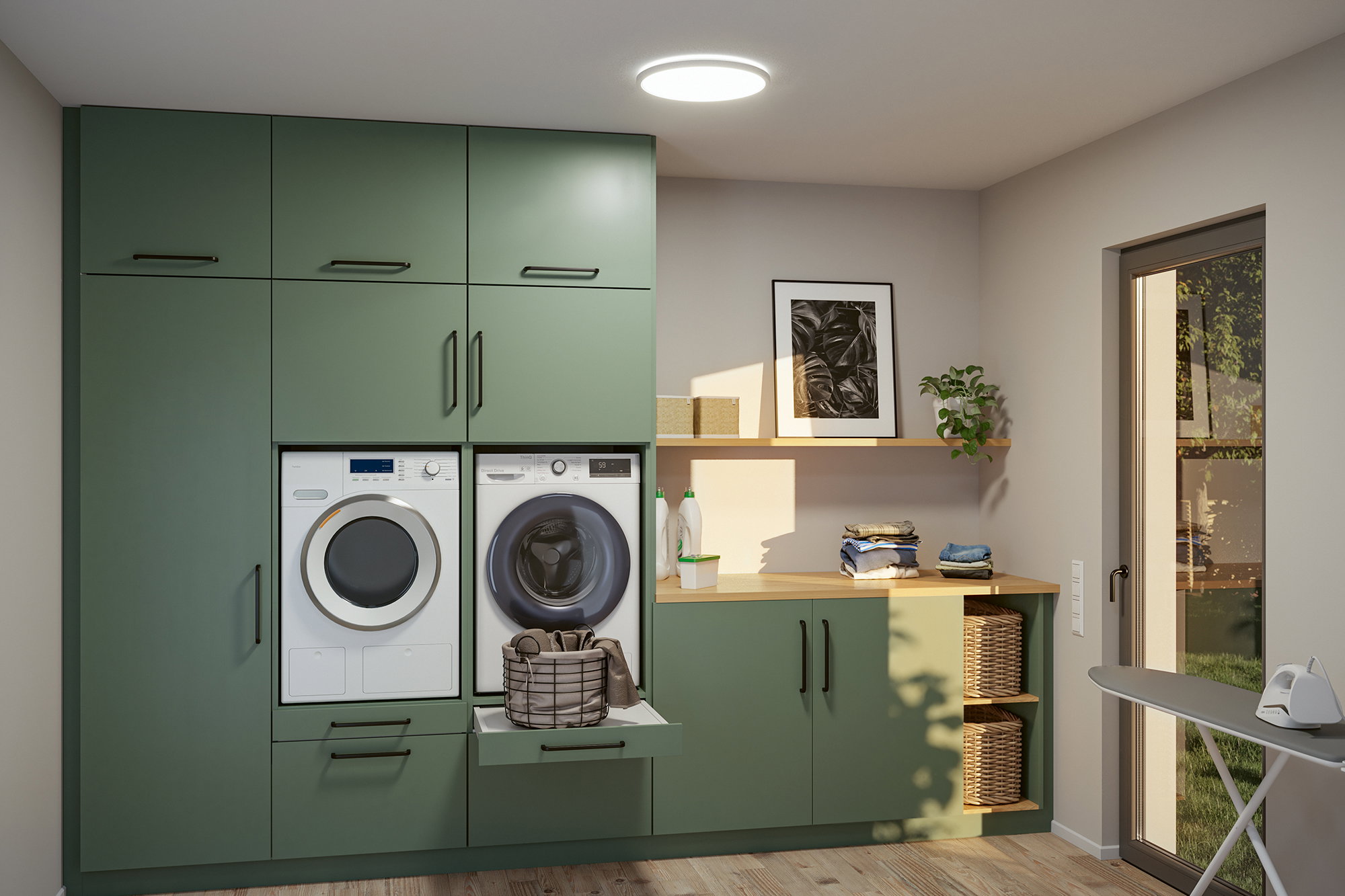 Buanderie moderne verte intégrée avec machine à laver, sèche-linge et plan de travail en bois dans une pièce lumineuse