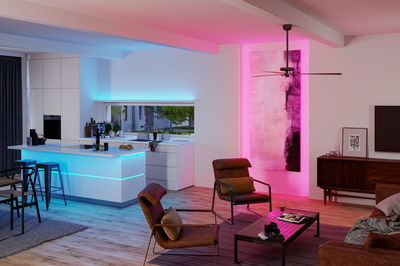 Modernes Wohnzimmer mit braunen Sesseln und LED-Streifenbeleuchtung in Blau und Pink für Wohnraumbeleuchtung