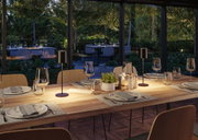 Modern wooden dining table with black LED table lamps and set places in cozy dining room lighting.
