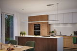 Moderne keuken met houten kasten en wit aanrecht, verlicht door slanke LED-hanglamp