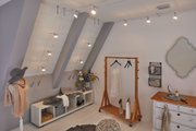 Modern dressing room with silver LED cable spotlights on ceiling and wooden clothes rack with dress