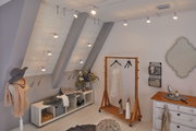 Modernes Ankleidezimmer mit silbernen LED-Seilstrahlern an der Decke und Holzgarderobe mit Kleid