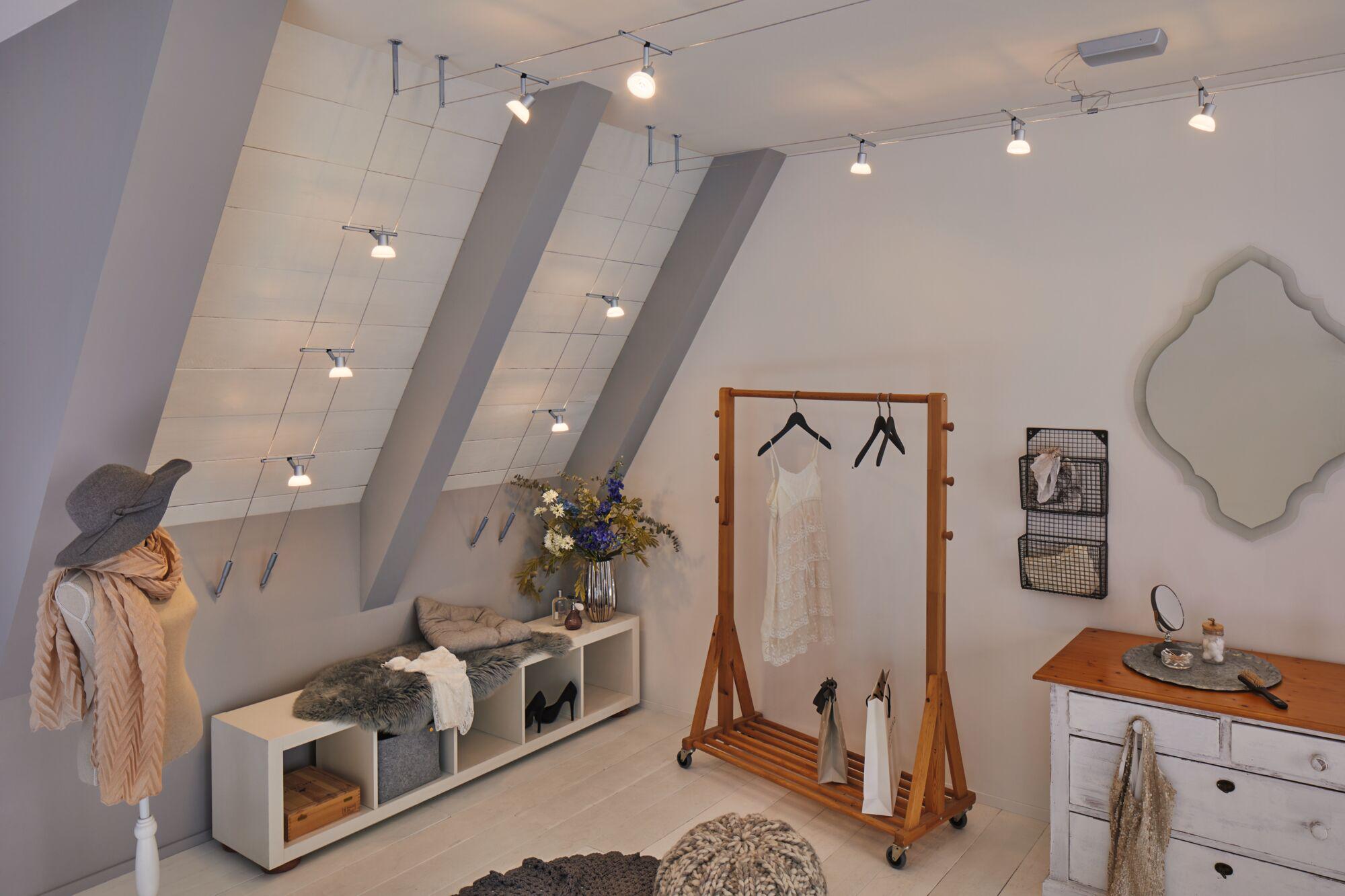 Modernes Ankleidezimmer mit silbernen LED-Seilstrahlern an der Decke und Holzgarderobe mit Kleid