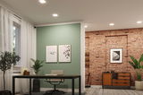 Moderne kantoorruimte met groene accentmuur, zwart bureau, grijze stoel en bakstenen muur met houten kast