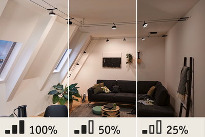 Moderne stue med sort sofa og dæmpbare LED-kabelspots i loftet med varmt hvidt lys