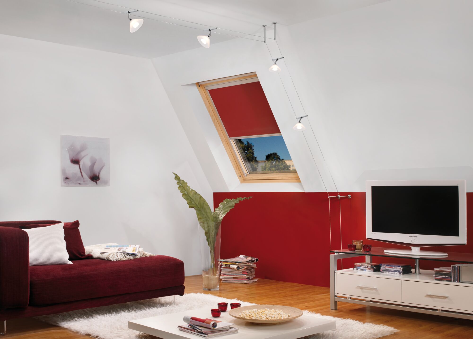 Moderne woonkamer met rode bank, wit vloerkleed en verstelbare kabelplafondlampen