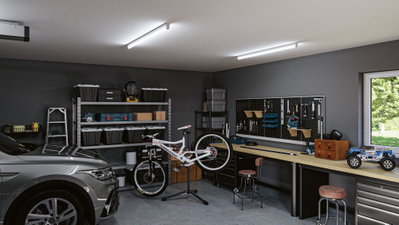 Moderne Garage mit grauem Auto, weißem Mountainbike auf Ständer und Werkbank mit Werkzeugwand.