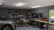 Modern garage with grey car, white mountain bike on stand, and workbench with tool board.