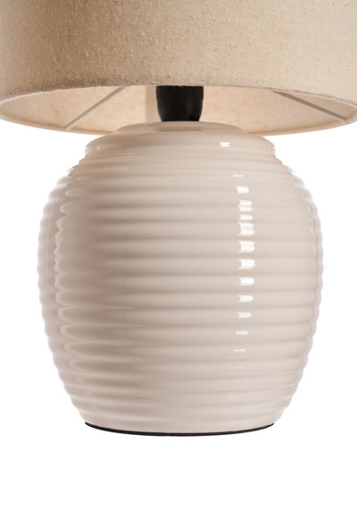Tafellamp met crèmekleurige keramische voet en beige stoffen kap voor sfeervolle verlichting