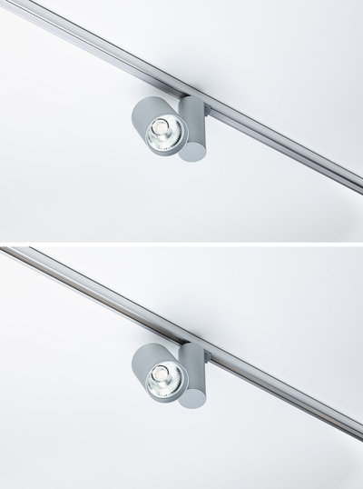Moderner grauer LED-Strahler aus Metall an Schienensystem für flexible Deckenbeleuchtung