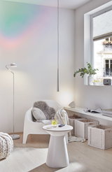 Modernes Wohnzimmer mit weißem Kunststoffstuhl, Beistelltisch und silberner Stehleuchte für gemütliche Beleuchtung