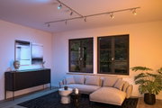 Modern silver metal ceiling spotlights in living room with grey sofa and black furniture