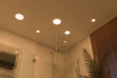 Modern bathroom with warm white LED recessed lights in ceiling and stainless steel rain shower.