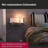 Wit wandplankje met verplaatsbare lichtmodule en lamp naast bed met grijze gebreide deken