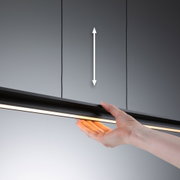 Main tenant un éclairage LED noir avec lumière blanche chaude sur fond gris, éclairage moderne
