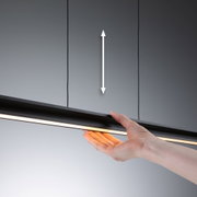 Hand hält schwarze LED-Leuchte mit warmweißem Licht vor grauem Hintergrund, moderne Beleuchtung