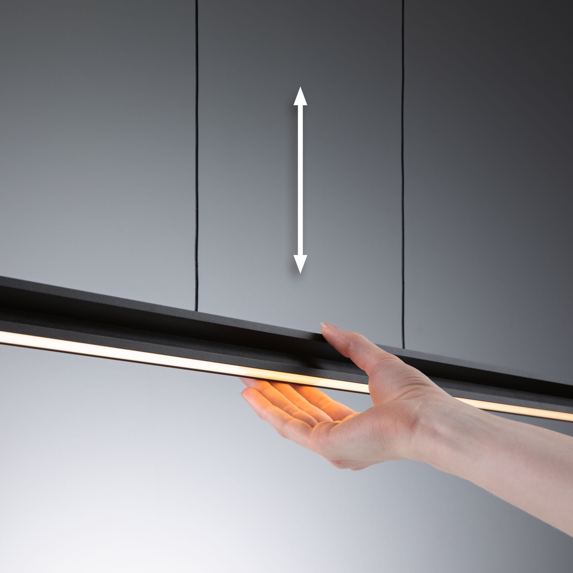 Hand hält schwarze LED-Leuchte mit warmweißem Licht vor grauem Hintergrund, moderne Beleuchtung