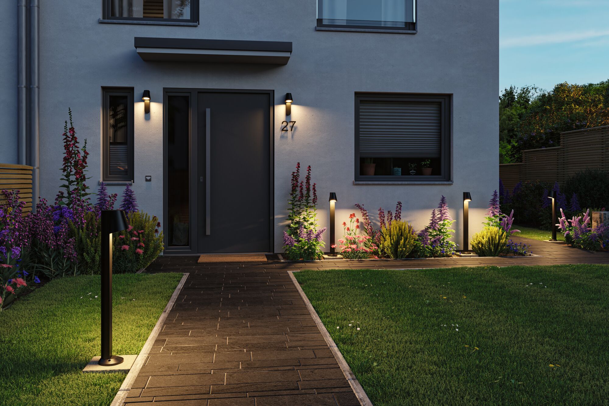 Moderne schwarze Außenwandleuchten und Pollerleuchten beleuchten den Hauseingang mit Gartenweg und Blumenbeeten.