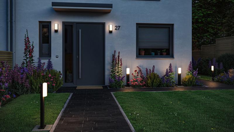 Éclairage extérieur moderne avec appliques murales LED noires et bornes lumineuses le long de la maison et du chemin.