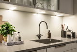 Moderne køkkenbordplade med sort vask, mat sort vandhane og LED-underkabinetbelysning.