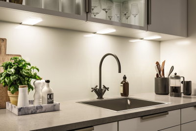Moderne køkkenbordplade med sort vask, mat sort vandhane og LED-underkabinetbelysning.