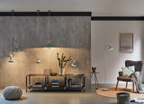 Modernes Wohnzimmer mit blauen Metalllampen, Stehlampe, Pendelleuchten und Tischlampe, Betonwand und grauem Sessel.