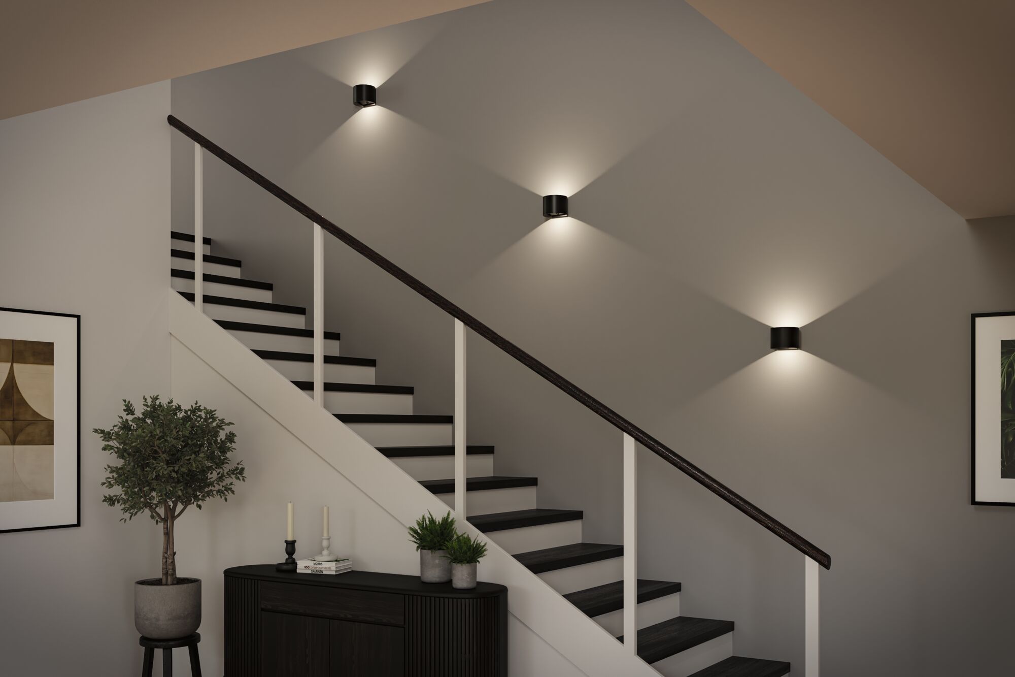 Modern staircase with black wooden handrail and three black metal wall lights emitting warm white light