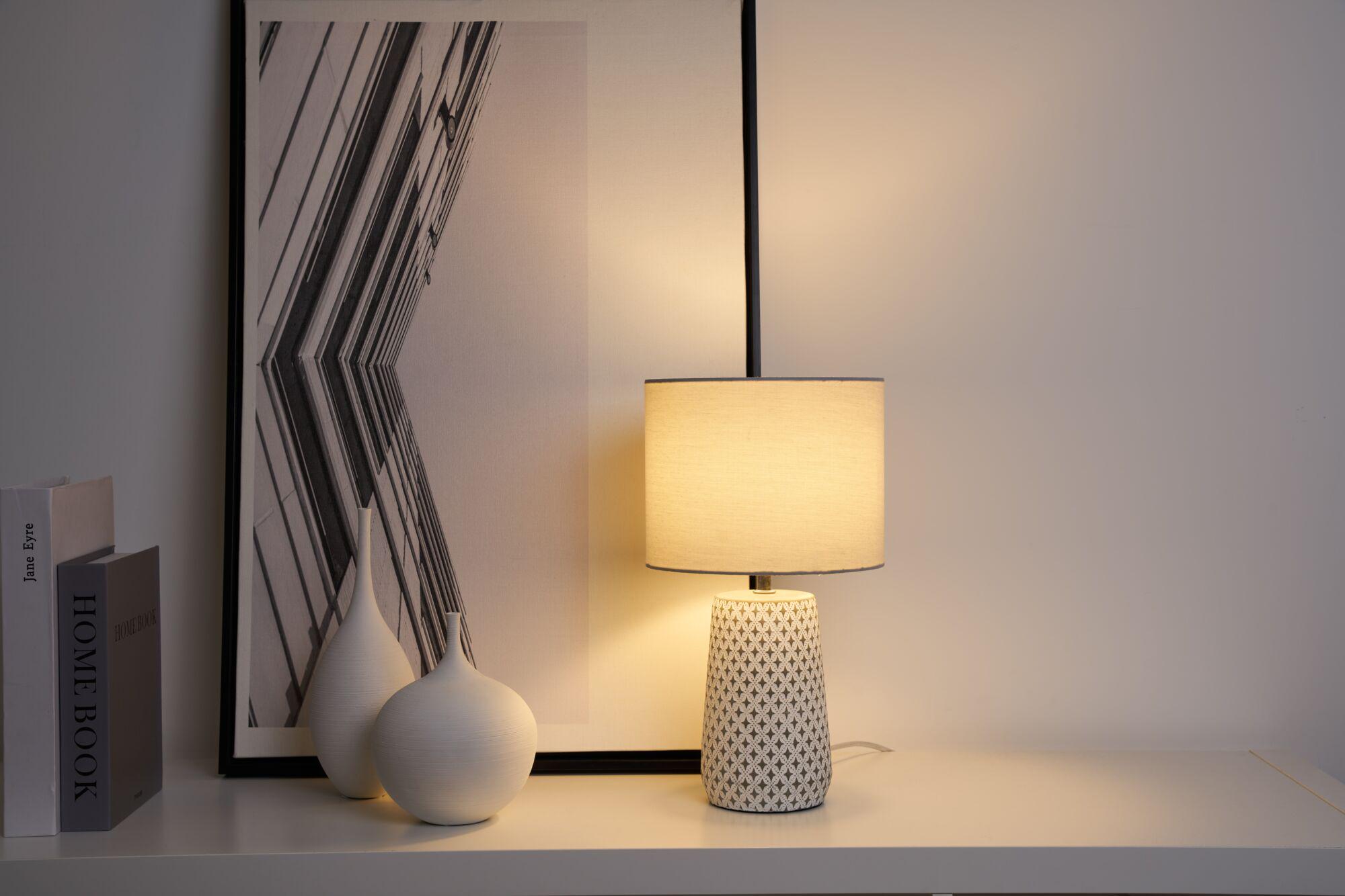 Ceramic table lamp with cream fabric shade and geometric pattern for ambient lighting in living spaces