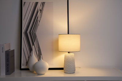 Ceramic table lamp with cream fabric shade and geometric pattern for ambient lighting in living spaces