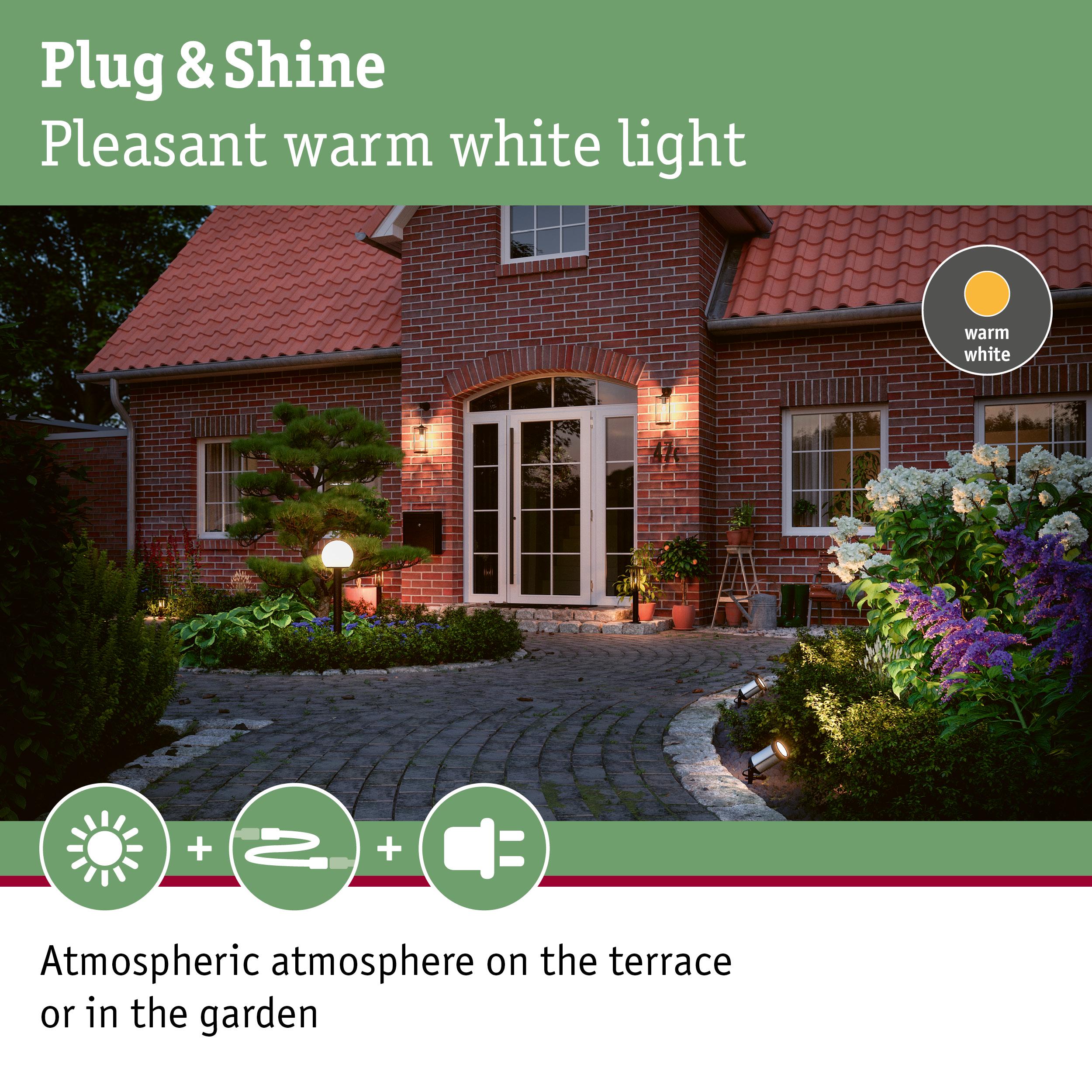 Warm white outdoor lighting creating atmospheric terrace and garden ambiance by red brick house