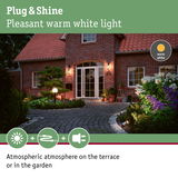 Warm white outdoor lighting creating atmospheric terrace and garden ambiance by red brick house