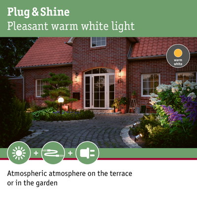 Red brick house with warm white outdoor lighting on terrace and garden for ambient garden lights