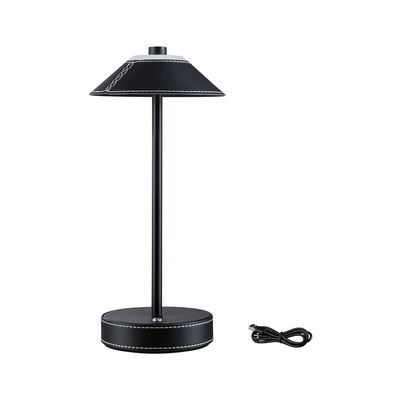 Black table lamp with leather cover and white stitching, including USB charging cable for modern lighting.