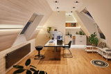 Modern home office with wooden floor, white desk, black chair, and indirect LED lighting