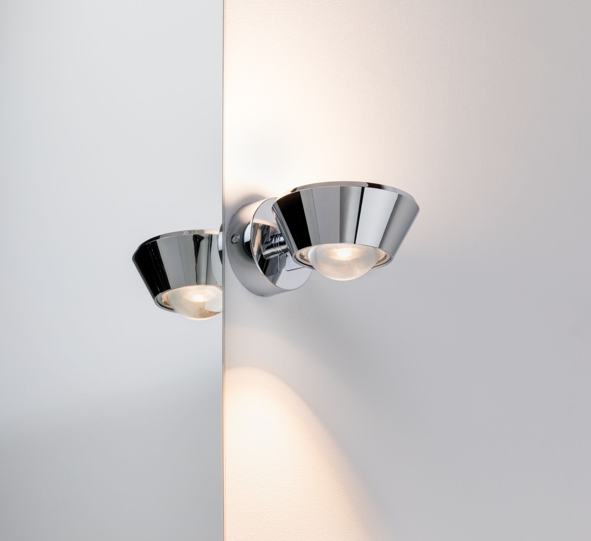Moderne wandspot van chroom metaal met kegelvormige reflector en warm wit licht