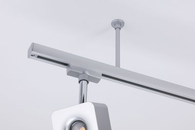 Modern silver metal LED track spotlight mounted on white ceiling for adjustable lighting