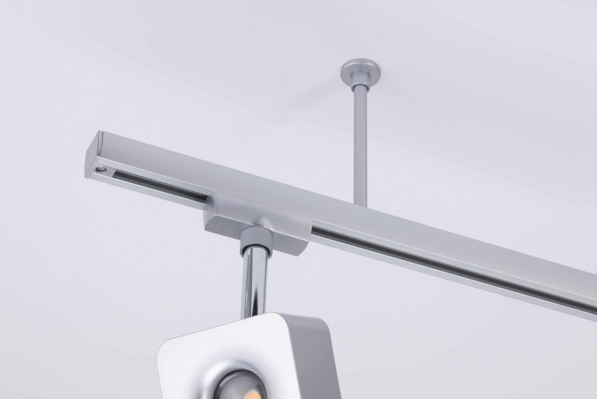 Modern silver metal LED track spotlight mounted on white ceiling for adjustable lighting