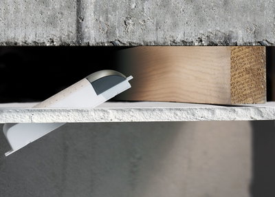 Connecteur mural en plastique blanc avec couvercle gris sur béton et bois pour systèmes d'éclairage LED.