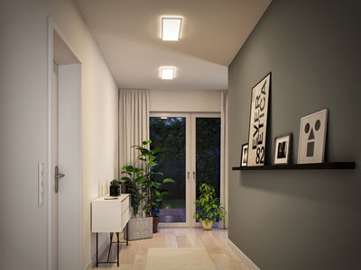 Moderner Flur mit weißen Deckenleuchten, grünen Pflanzen und minimalistischer Einrichtung in warmem Licht.