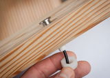 Hand attaching black cable gland with white plastic on light wood panel for LED lighting setup