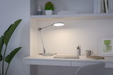 Moderne witte metalen bureaulamp met ronde lichtkop op minimalistische werkplek.