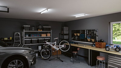 Moderne Garage mit grauem Auto, weißem Fahrrad auf Ständer und Werkbank mit Werkzeugwand und LED-Deckenleuchten