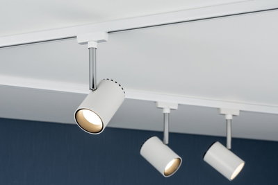 Drei weiße LED-Strahler aus Metall an Schienensystem vor dunkelblauer Wand für Akzentbeleuchtung