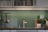 Cuisine moderne avec robinet en acier inoxydable, crédence en verre vert et éclairage LED sous meuble