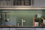 Modern kitchen with stainless steel faucet, green glass backsplash and LED under-cabinet lighting