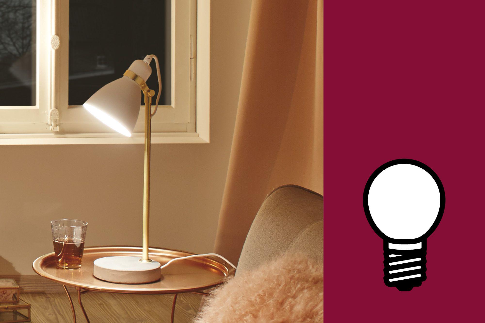 Lampe de table moderne avec abat-jour blanc en métal et pied doré sur table d'appoint cuivre.