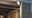 White plastic outdoor wall light on modern wooden terrace illuminating entrance, LED outdoor lighting.