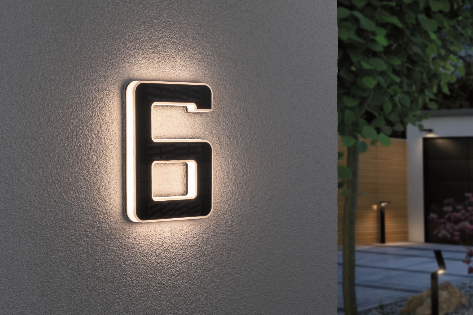 Illuminated house number 6 in black with warm white LED light on exterior wall.