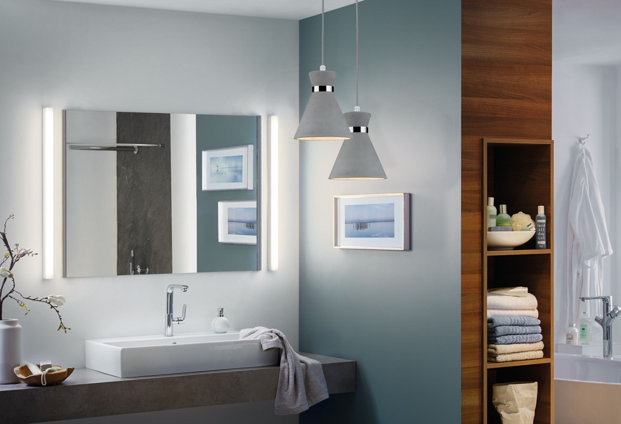 Moderne badkamer met witte wastafel, grijs betonnen aanrecht en twee grijze betonnen hanglampen.