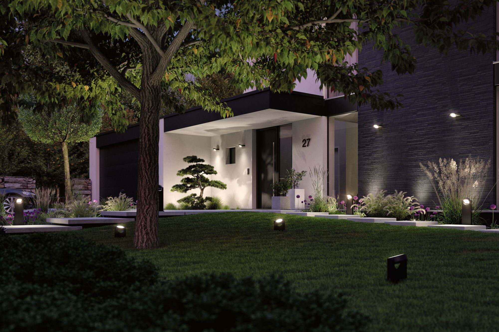 Moderne Außenbeleuchtung mit schwarzen LED-Strahlern beleuchtet Gartenweg und Hausfassade bei Nacht